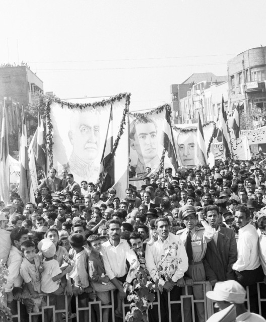 Hundreds of people hold banners in a city square.