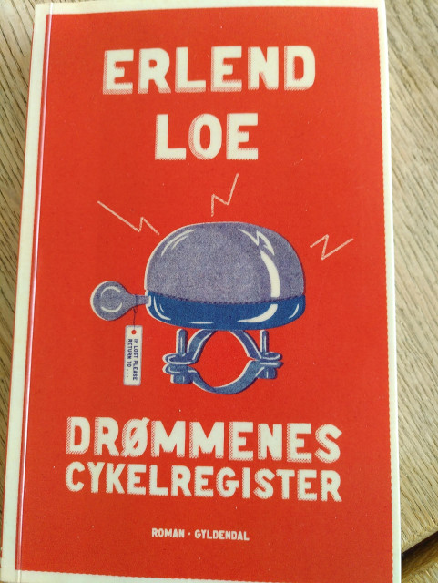 Forsiden af bogen "Drømmenes Cykelregister" af Erlend Loe. Der er en tegning af en cykelklokke med en label hvorpå der står "if lost return to...". Baggrunden er rød og teksten hvid.