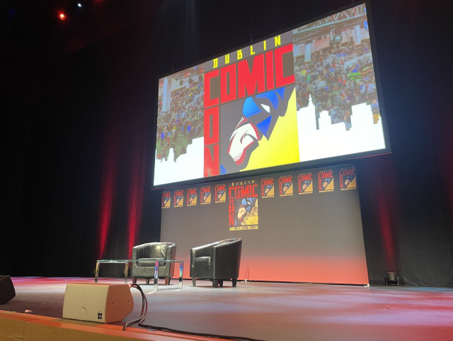 Main stage of Dublin Comic Con with two leather chairs and a small table.