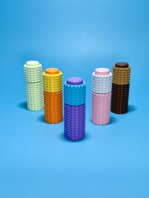 On a baby blue background: 3 in 1 spiky ‘ouchie’ style spiky sensory tool. There is a clicker in the top and it also has a real ball bearing installed so the top 1/3rd of it spins. 

It’s also printed with extra weight, weighing roughly 40 grams, to give it a more sturdy and solid feel. 

Available in ‘ice cream’ colour themes: cotton candy, strawberry, chocolate, mango, and mint. 