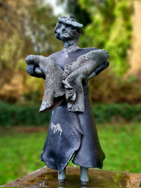 A statue of a woman dressed in 1920s clothinh holding two babies.