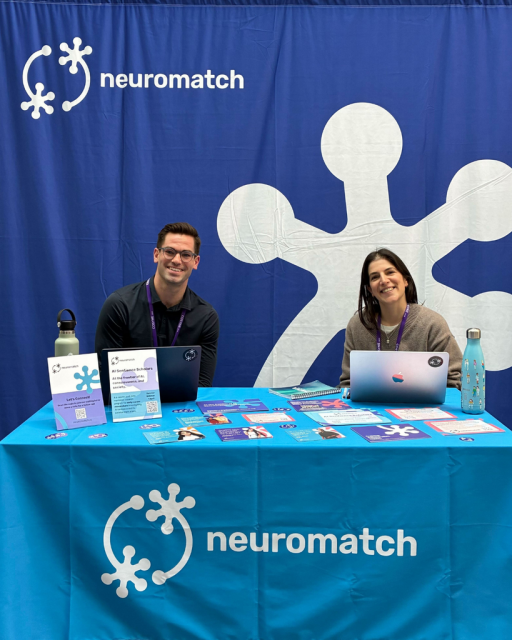 Bradley Roberts (CEO) and Joana Guedes (Program Manager) seated at the  Neuromatch branded booth.