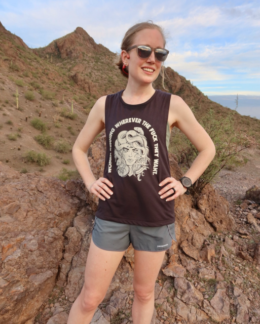 Woman in running gear pausing on a trail in the desert
