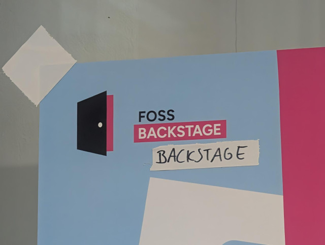 Poster with the conference logo and piece of tape  that has written the word backstage on it