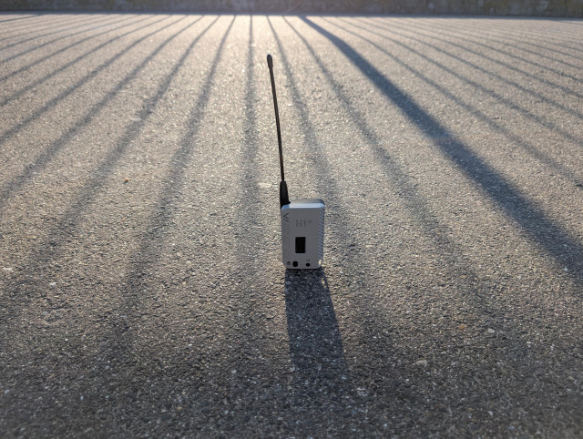 Ein Graues Gehäuse mit Antenne steht auf einer Straße.