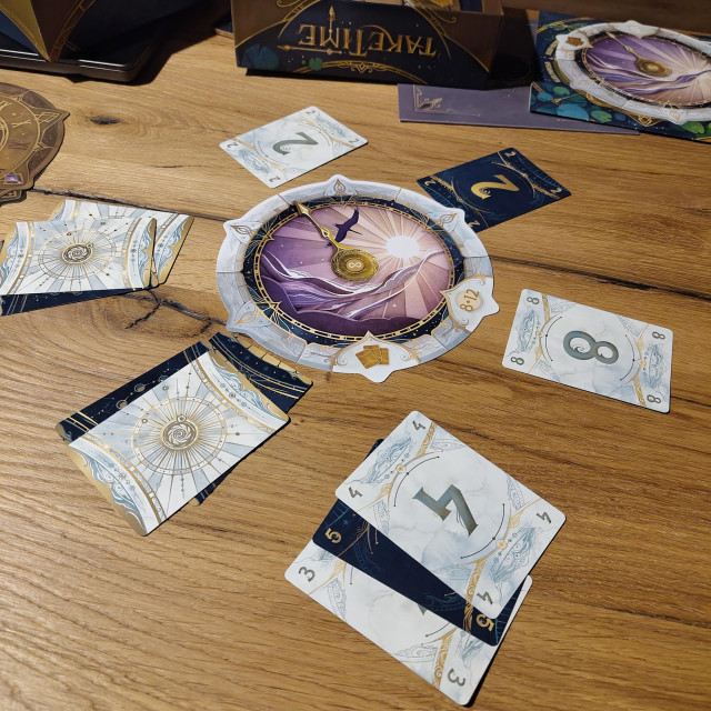 A stylized clock in the middle surrounded by 12 cards in groups, some of them turned. It's a really nice dreamy design, mostly in dark blue, white and gold. 