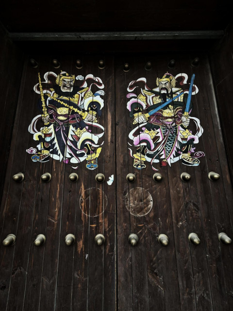 Heavy, studded wooden doors with brightly colored warrior motif.