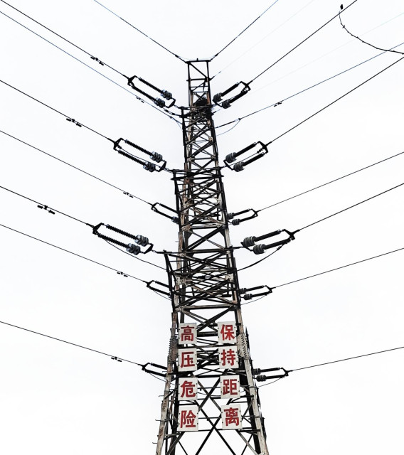 A pylon, alone against the pale, cloudless sky