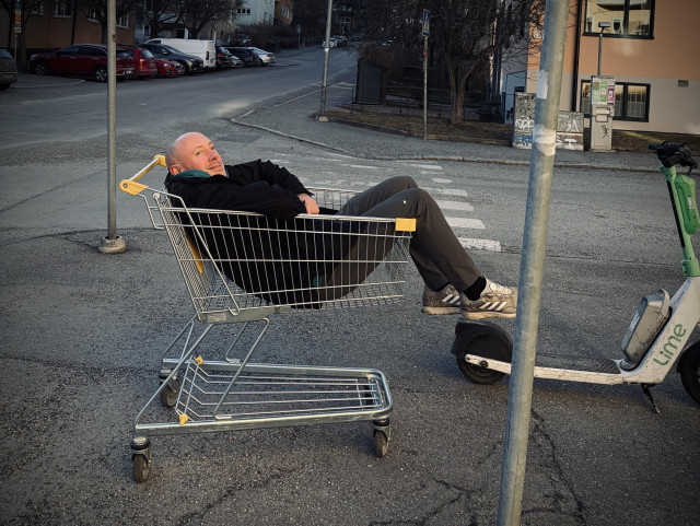 Man sitting in a shopping cart on the street