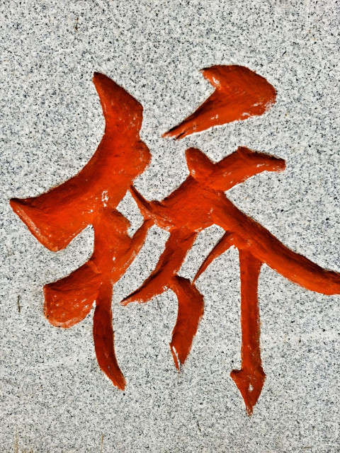 Character meaning bridge painted bright red and cut into speckled stone.
