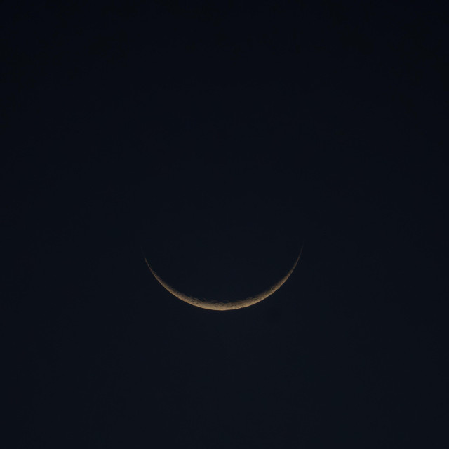 low slung fine crescent moon in dark sky