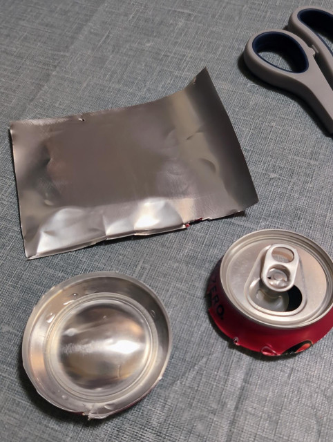 A soda can with the top and bottom cut off, laid out as a flat rectangle.