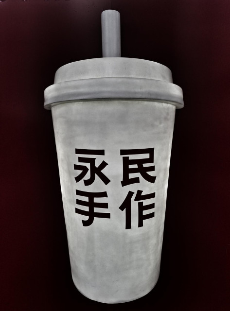Giant statue of a takeaway fast food beverage holder with Chinese characters on it.
