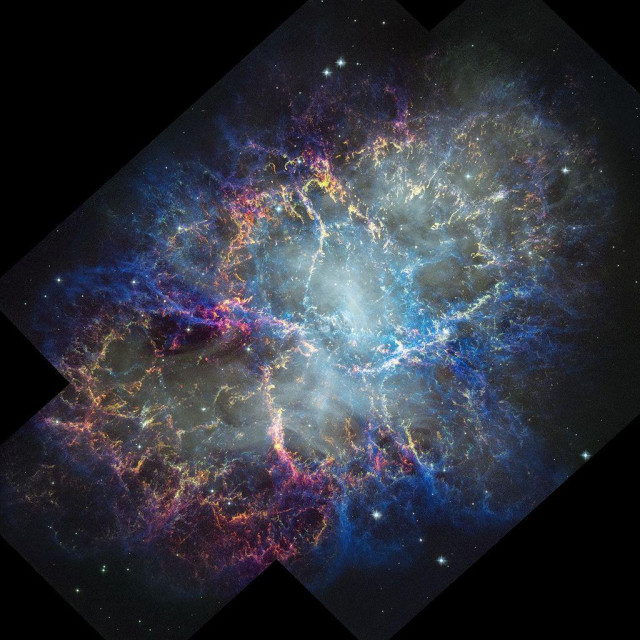 Colorful nebula in space with a white haze throughout that is more concentrated in the center with a rippling effect. Colorful gas filaments appear to splash outward from the nebula center, colored yellow, magenta, and blue. A faint black border with right angles at the corners of the images show where the telescope's field of view stops. Small white stars dot the background.