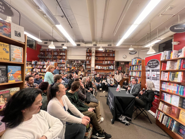 An audience sits in front of Cindy Cohn and Jonathan Zittrain, who sit behind a table in the Harvard Book Store, surrounded by bookshelves.