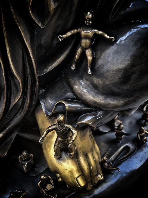 Brass Buddha statue with tiny figurinea crawling on body