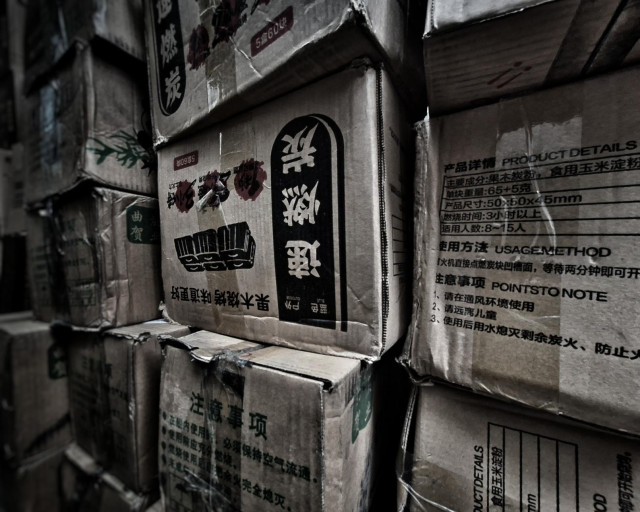 A wall of crumbled boxes with Chinese characters on them.