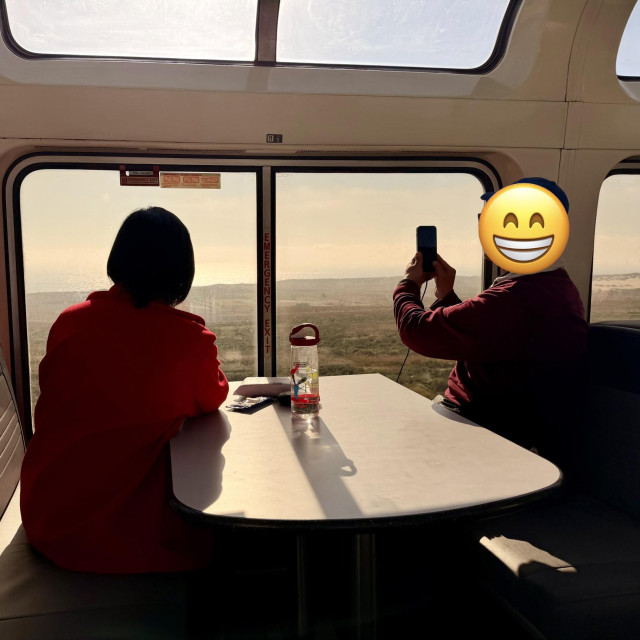 A photo of people taking photos of the ocean from inside the coast starlight observation car 