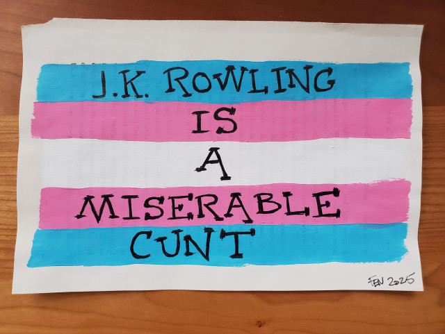 A trans flag painted on pages torn from a harry potter book. In the harry potter font is written, JK Rowling is a Miserable Cunt.