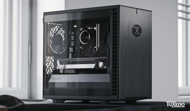 A computer with a transparent side panel and a Tuxedo logo on the front, sitting on a desk 