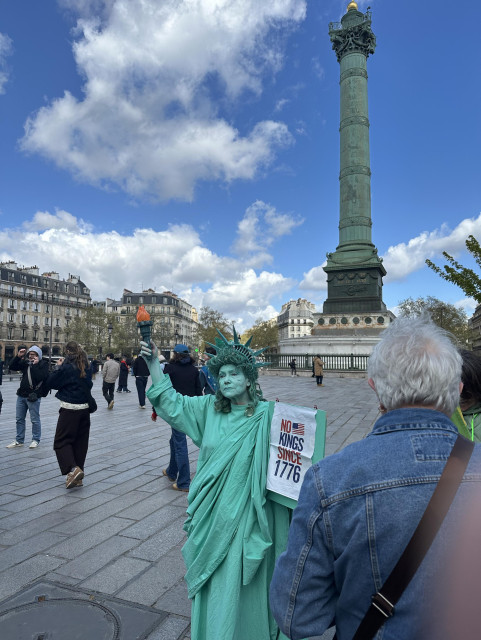 A woman dressed as the Statue of Liberty in front of the Bastille monument in Paris. March 28, 2026