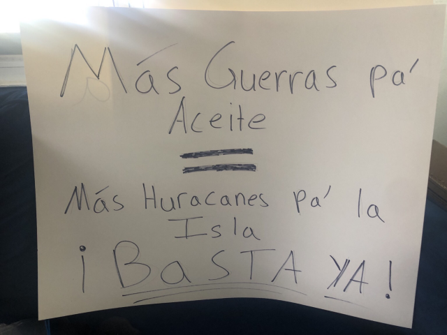 Protest sign that reads Mas Guerras Pa’ Aceite = Mas huracanes pa la Isla