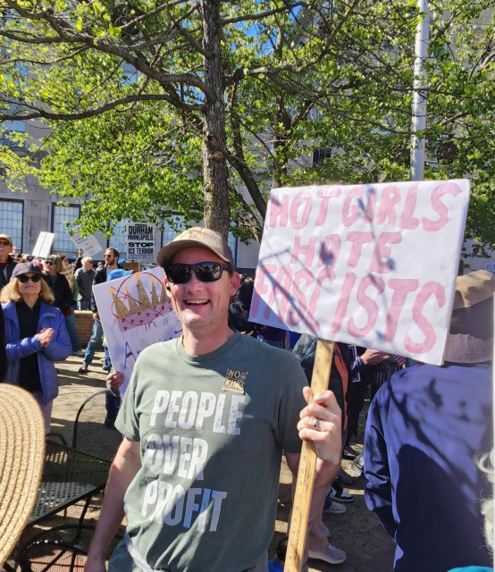 Me at the protest wearing a “People Over Profit” t-shirt and holding a “Hot Girls Hat Fascists” sign. 