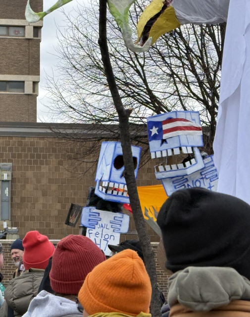 Photo zoomed in on some protest puppets, skulls made of cardboard boxes