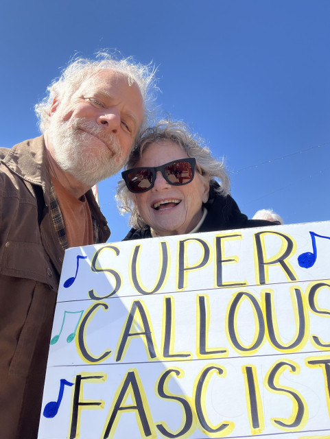 a smiling middle ages man with a smiling older woman holding up a sign ("super callous fascist...."