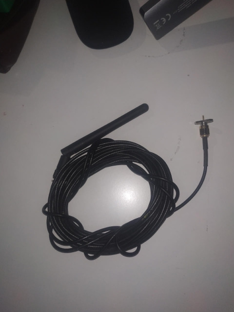 Na białym blacie ciasno zwinięty czarny przewód, z jednej strony zakończony wtyczką i gniazdem antenowym, a z drugiej plastikową antenka wielkości środkowego palca.