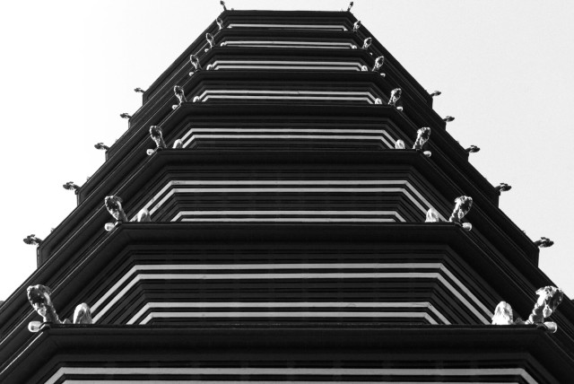 High-contrast black and white photo looking up at Kew Garden's Great Pagoda; the lens and perspective have reduced it to white squared-off parentheses on a black background against a white sky.