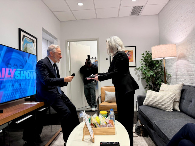 EFF's Cindy Cohn presenting a "Let's Sue the Government" shirt to Jon Stewart in the green room at The Daily Show