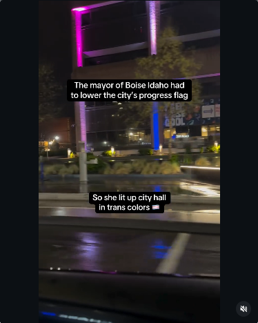 Still of the video showing floodlights outside Boise City Hall creating pillars of blue, white and pink light between rows of windows. It's not a trans flag, oh no. They got around the state law again!