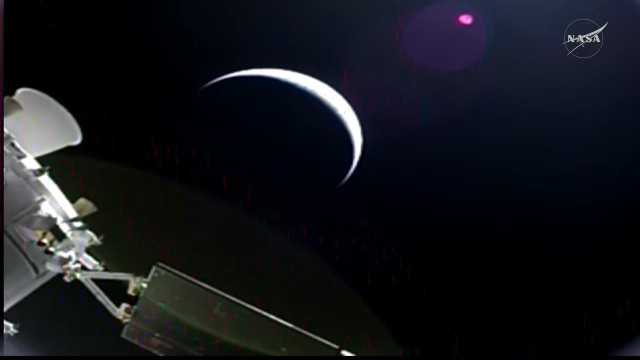 Still from the webcast showing parts of the spacecraft and a crescent earth in the distance,