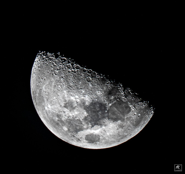 Black and white photo of the moon with a little more than half of its surface lit by sunlight.