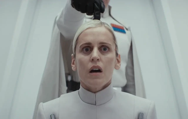 Dedra Meero in utter shock as Krennic interrogates her, pointing his index finger on top of her head from behind