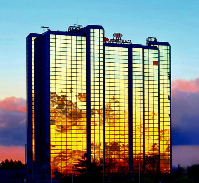 A sunset reflected in the glass of a modern hotel building.