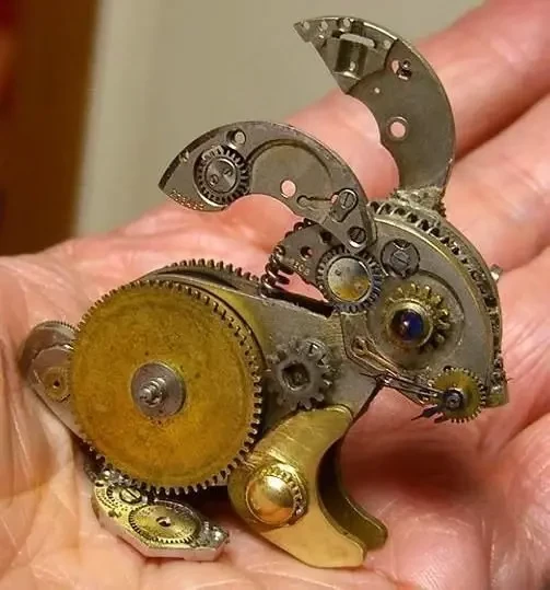 Small rabbit sculpture made from brass cogs sitting on the palm of a hand