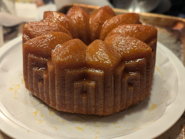 an orangey-brown bundt cake, pictured from the side to show off the side details. the cake has a large ten-petal flower on top, with small stairstep shapes along the edges.