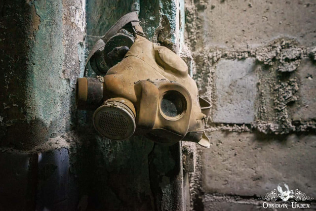 An old, tan Soviet-era gas mask hangs on a weathered wall