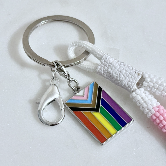 A close up of the ring, lobster clip, and pride flag charm