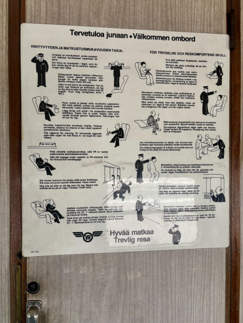 Lättähatun matkustamon seinällä juliste, jossa on ohjeita junamatkustajille.