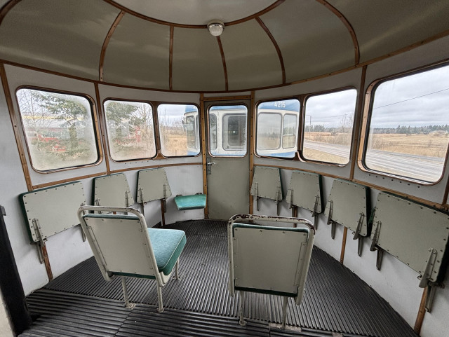 Lättähattuvaunun eteinen. Puolipyöreän tilan seinustoilla ikkunoita ja niiden alla ylöskäännettyjä istuimia.