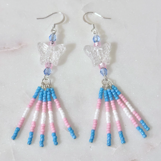 A pair of drop earrings in the trans pride colors with white/clear butterfly beads