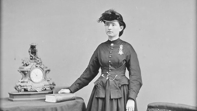 Dr Mary Edwards Walker with her medal. She is a white woman with dark hair. She's wearing a dress and looking miserable about it.
