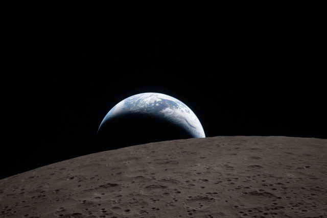 

art002e009288 (April 6, 2026) – Earthset captured through the Orion spacecraft window at 6:41 p.m. EDT, April 6, 2026, during the Artemis II crew’s flyby of the Moon. A muted blue Earth with bright white clouds sets behind the cratered lunar surface. The dark portion of Earth is experiencing nighttime. On Earth’s day side, swirling clouds are visible over the Australia and Oceania region. In the foreground, Ohm crater has terraced edges and a flat floor interrupted by central peaks—formed when the surface rebounded upward during the impact that created the crater.

Image Credit: NASA