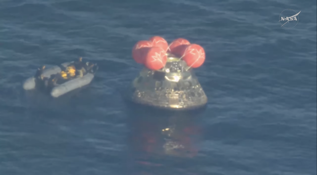 A boat directly next to the Integrity capsule, still floating, hatch closed, in the water.