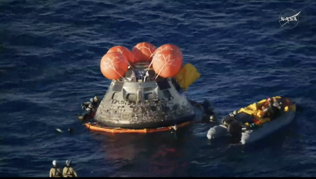 An orange ring around the Integrity capsule now, with divers in the water around it. apparently this is part of the front porch. 