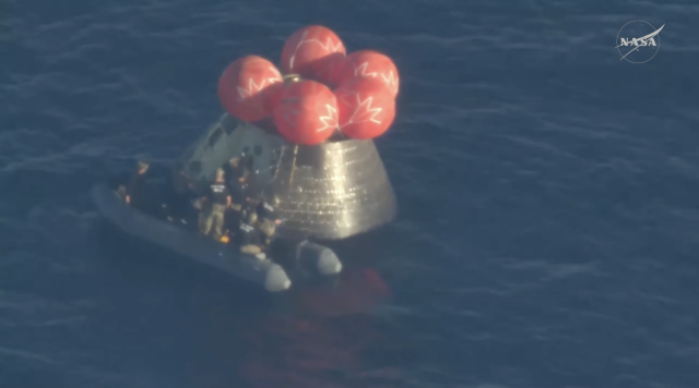 the floaty boat hooking up to the front door of the integrity capsule, seen from three-quarters above