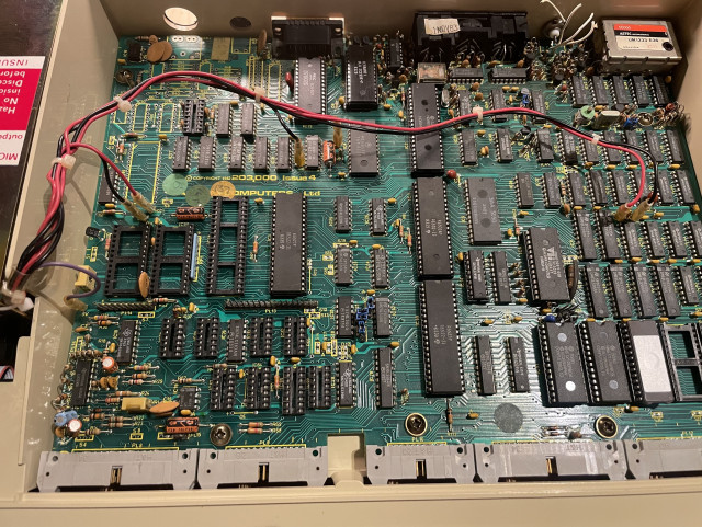 Photo of BBC Micro B motherboard showing the seven wires from the power supply connected to different parts of the board.